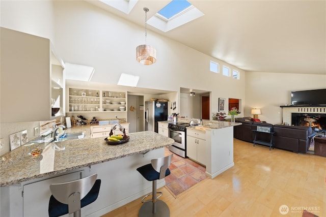 145 Lummi Dr, La Conner, WA 98257 - kitchen with appliances with stainless steel finishes, a peninsula, a skylight, a high ceiling, and hanging light fixtures