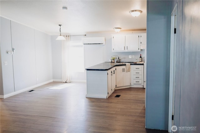 8805 226th Street Ct E Unit 32, Graham, WA 98338 - kitchen with a wall mounted AC, dark countertops, wood finished floors, white cabinets, and a peninsula