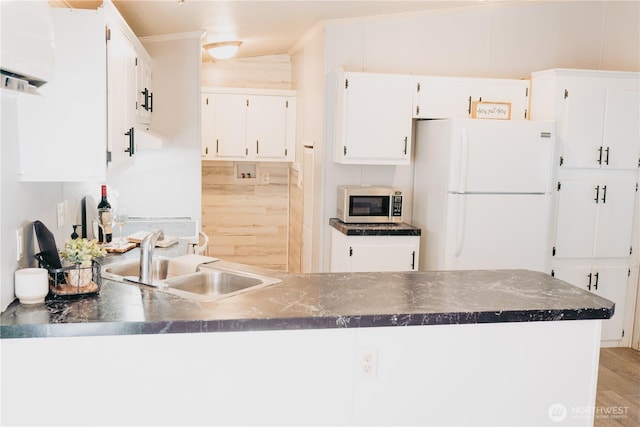 8805 226th Street Ct E Unit 32, Graham, WA 98338 - kitchen with freestanding refrigerator, dark countertops, a peninsula, white cabinetry, and light wood finished floors