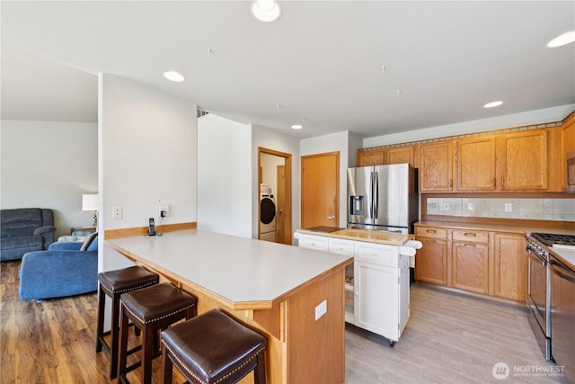 3519 G Ave, Anacortes, WA 98221 - kitchen featuring appliances with stainless steel finishes, light wood-style floors, a peninsula, light countertops, and a breakfast bar area
