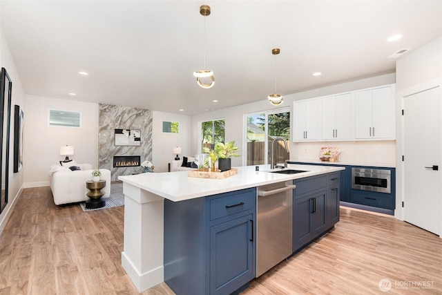1515 243rd Pl SW Unit A, Bothell, WA 98012 - kitchen featuring stainless steel appliances, a fireplace, light wood-style flooring, white cabinets, and recessed lighting