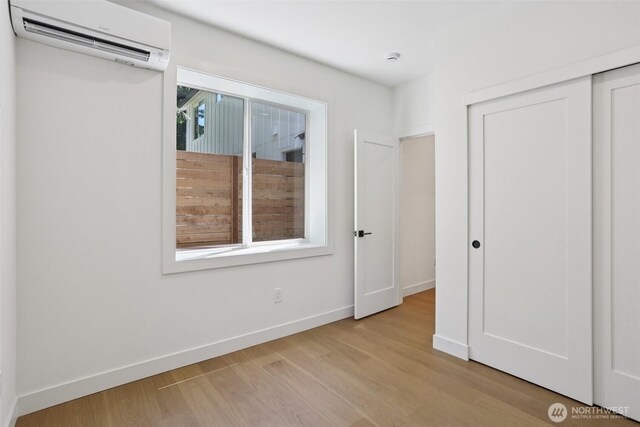 11737 38th Ave NE Unit A, Seattle, WA 98125 - unfurnished bedroom with a wall mounted air conditioner, light wood finished floors, and a closet