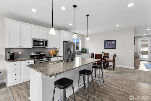 397 N Foster St, Buckley, WA 98321 - kitchen with appliances with stainless steel finishes, a center island with sink, light wood-style flooring, a kitchen bar, and white cabinets
