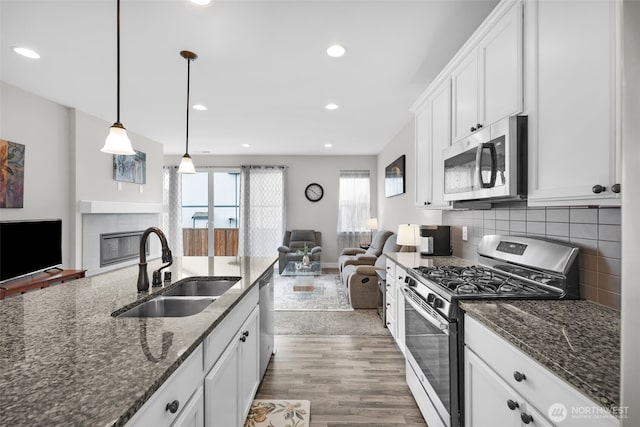 397 N Foster St, Buckley, WA 98321 - kitchen with stainless steel appliances, open floor plan, a fireplace, wood finished floors, and white cabinets
