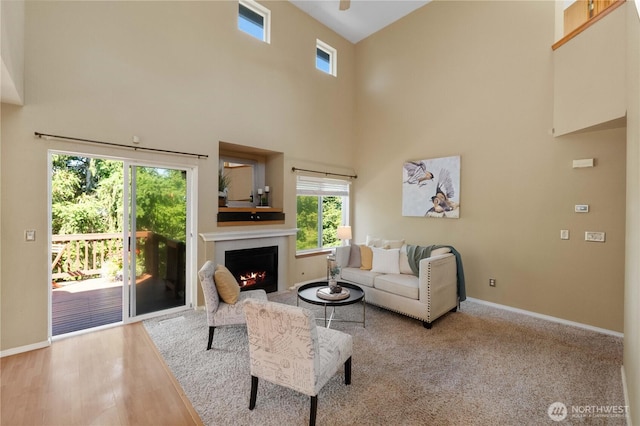 2819 Z St SE, Auburn, WA 98002 - living room featuring healthy amount of natural light, a towering ceiling, a warm lit fireplace, a ceiling fan, and wood finished floors