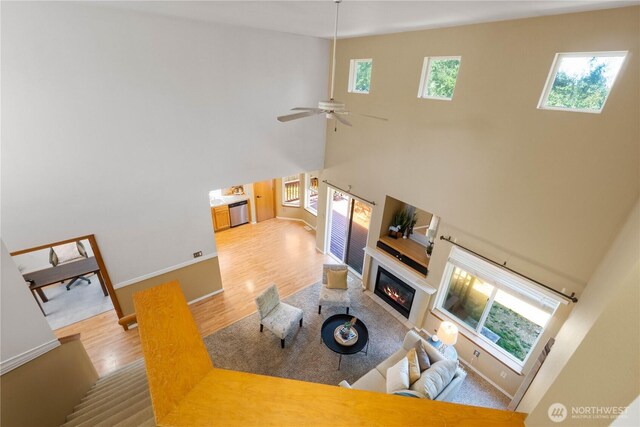 2819 Z St SE, Auburn, WA 98002 - living room featuring wood finished floors, a glass covered fireplace, a high ceiling, and ceiling fan