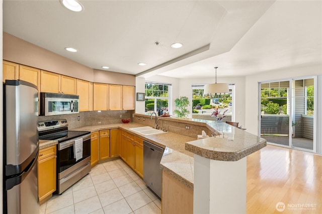 2244 SE 132nd Ave Unit B217, Bellevue, WA 98005 - kitchen featuring appliances with stainless steel finishes, tile counters, a peninsula, light brown cabinetry, and tasteful backsplash