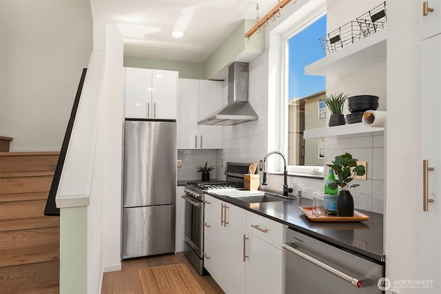 2610 E Yesler Way Unit A, Seattle, WA 98122 - kitchen featuring stainless steel appliances, wall chimney range hood, backsplash, dark countertops, and white cabinetry