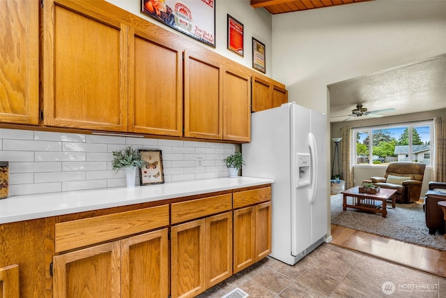 1702 7th Ave SW, Puyallup, WA 98371 - kitchen featuring white refrigerator with ice dispenser, brown cabinets, decorative backsplash, light countertops, and ceiling fan