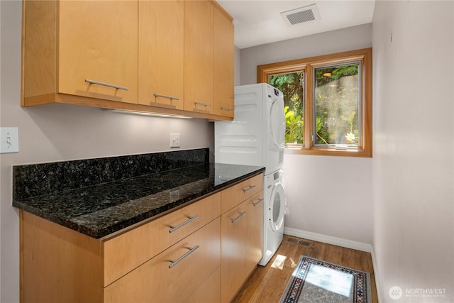 1823 121st Ave SE, Bellevue, WA 98005 - kitchen with estacked washer and dryer, wood finished floors, dark stone countertops, and light brown cabinets