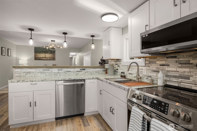 8730 206th St SE Unit 10, Snohomish, WA 98296 - kitchen with appliances with stainless steel finishes, tasteful backsplash, a peninsula, white cabinets, and light wood-style flooring