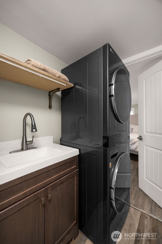 8730 206th St SE Unit 10, Snohomish, WA 98296 - washroom with stacked washer and clothes dryer, cabinet space, and light wood-type flooring