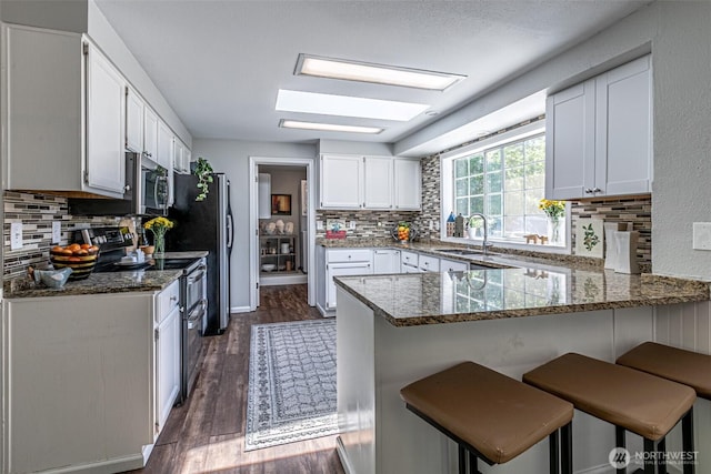18920 217th Ave E, Orting, WA 98360 - kitchen with stainless steel appliances, a peninsula, decorative backsplash, and dark stone counters