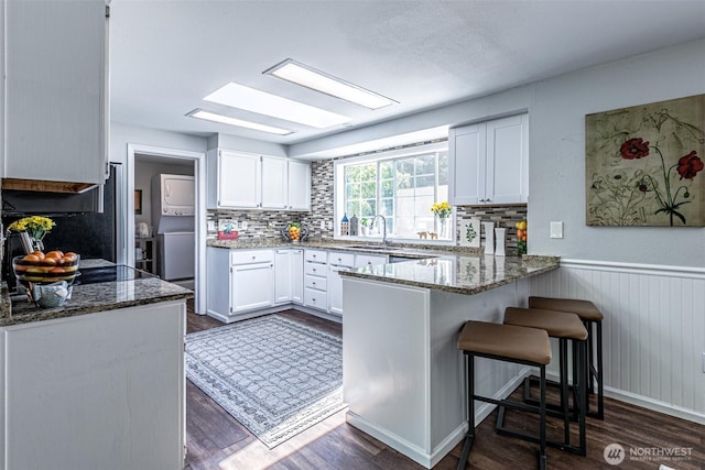 18920 217th Ave E, Orting, WA 98360 - kitchen with a peninsula, stone counters, dark wood-style floors, tasteful backsplash, and a wainscoted wall