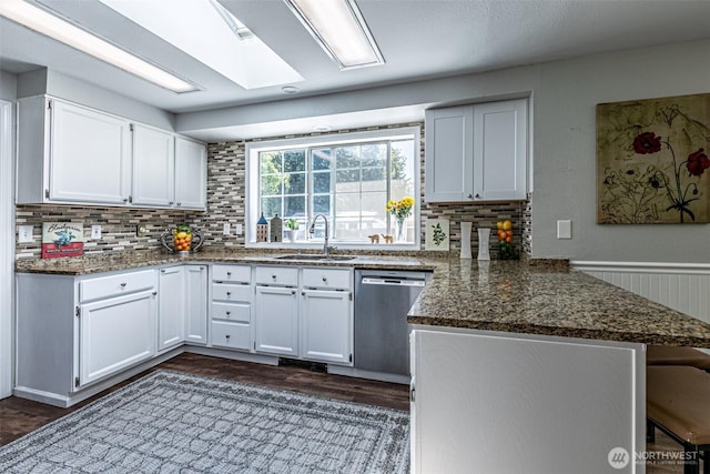 18920 217th Ave E, Orting, WA 98360 - kitchen featuring stainless steel dishwasher, a peninsula, decorative backsplash, white cabinets, and dark stone counters