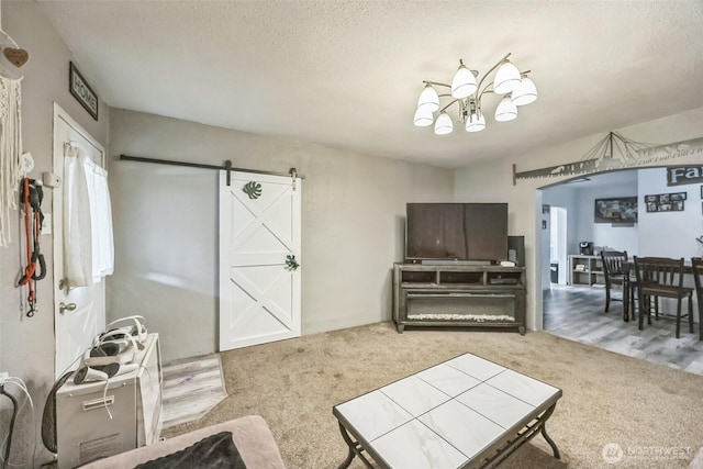 610 Westlake Ave, Morton, WA 98356 - living room featuring carpet flooring, a barn door, a chandelier, arched walkways, and a textured ceiling