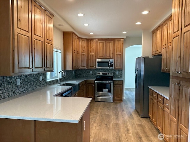 2101 S 324th St Unit 228, Federal Way, WA 98003 - kitchen featuring stainless steel appliances, arched walkways, recessed lighting, light wood-type flooring, and backsplash