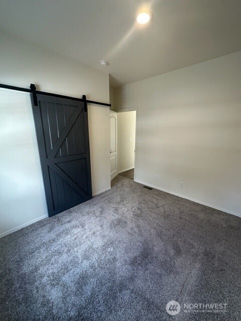 2101 S 324th St Unit 228, Federal Way, WA 98003 - unfurnished bedroom featuring carpet and a barn door