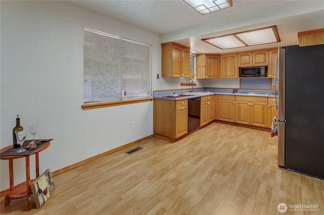 7127 Fair Oaks Loop SE, Olympia, WA 98513 - kitchen with black microwave, freestanding refrigerator, dishwasher, light wood-style flooring, and cooktop