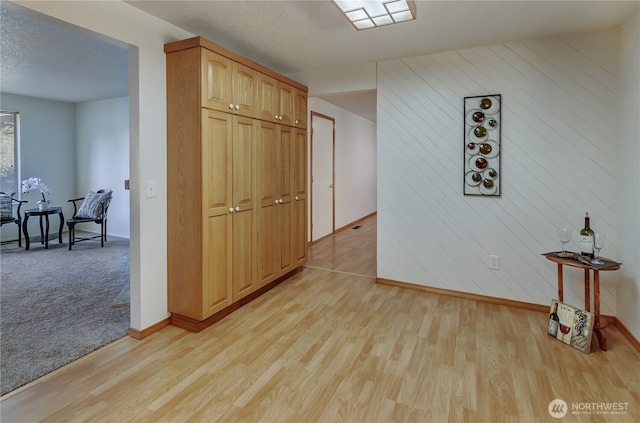 7127 Fair Oaks Loop SE, Olympia, WA 98513 - corridor featuring light wood-style flooring, a textured ceiling, and wooden walls