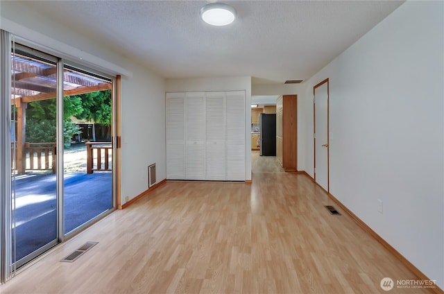 7127 Fair Oaks Loop SE, Olympia, WA 98513 - unfurnished bedroom featuring freestanding refrigerator, light wood-style flooring, access to exterior, a textured ceiling, and a closet