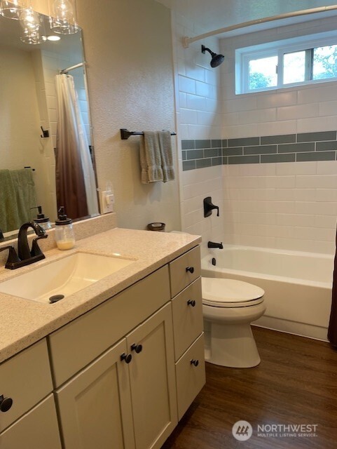 20011 Tveit Rd, Arlington, WA 98223 - bathroom featuring vanity, wood finished floors, and shower / bathtub combination with curtain