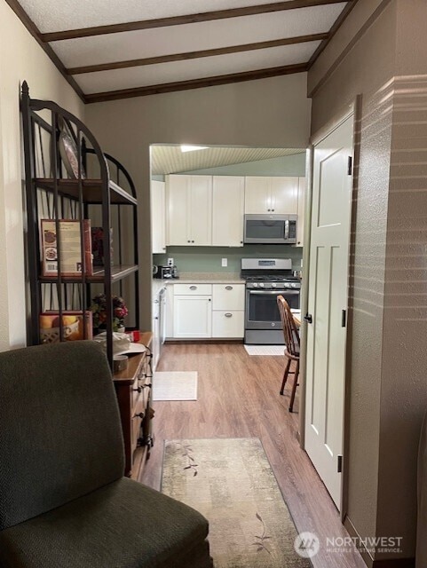 20011 Tveit Rd, Arlington, WA 98223 - kitchen with appliances with stainless steel finishes, light wood-type flooring, white cabinetry, light countertops, and crown molding