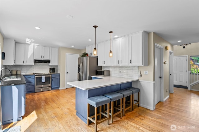 5115 150th St SE, Everett, WA 98208 - kitchen with appliances with stainless steel finishes, backsplash, a breakfast bar area, light wood-type flooring, and recessed lighting