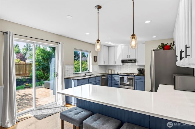 5115 150th St SE, Everett, WA 98208 - kitchen featuring stainless steel appliances, a peninsula, a breakfast bar, white cabinetry, and light wood finished floors