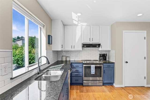 5115 150th St SE, Everett, WA 98208 - kitchen featuring stainless steel range with electric stovetop, under cabinet range hood, blue cabinetry, white cabinets, and dark stone countertops