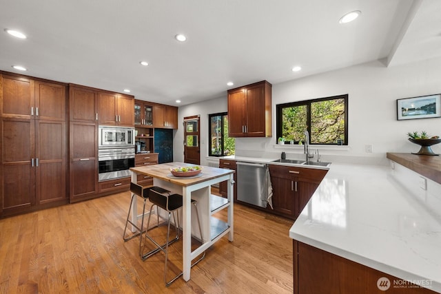 3516 NE 43rd St, Seattle, WA 98105 - kitchen with stainless steel appliances, light countertops, light wood-style floors, recessed lighting, and glass insert cabinets