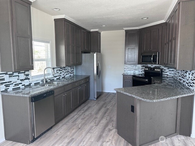2101 S 324th St Unit 193, Federal Way, WA 98003 - kitchen featuring stainless steel appliances, dark stone counters, decorative backsplash, a peninsula, and a textured ceiling
