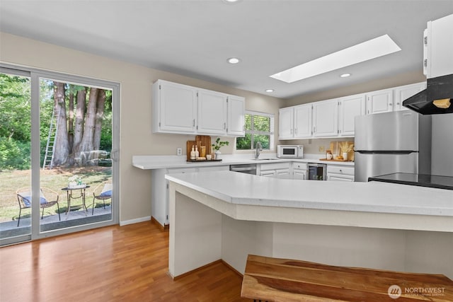 8618 212th St NE, Arlington, WA 98223 - kitchen with stainless steel appliances, a skylight, light countertops, wine cooler, and white cabinets