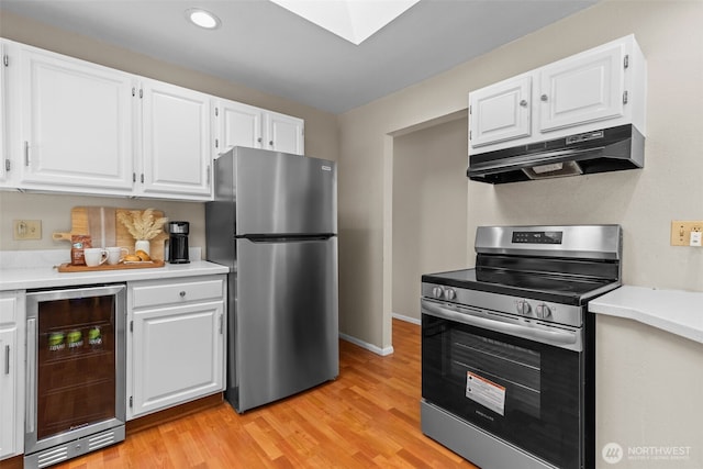 8618 212th St NE, Arlington, WA 98223 - kitchen with stainless steel appliances, beverage cooler, under cabinet range hood, light countertops, and white cabinets