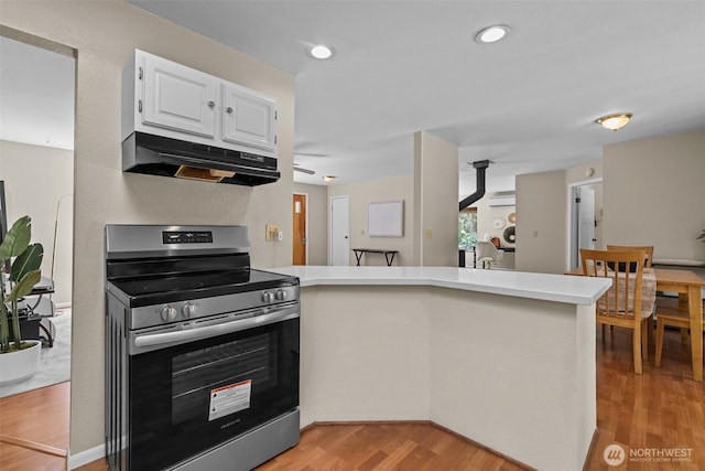 8618 212th St NE, Arlington, WA 98223 - kitchen with electric stove, under cabinet range hood, a peninsula, light wood-type flooring, and white cabinets