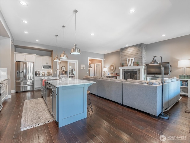 2038 Maiden Ln, Wenatchee, WA 98801 - kitchen featuring stainless steel appliances, a breakfast bar area, open floor plan, white cabinets, and a stone fireplace