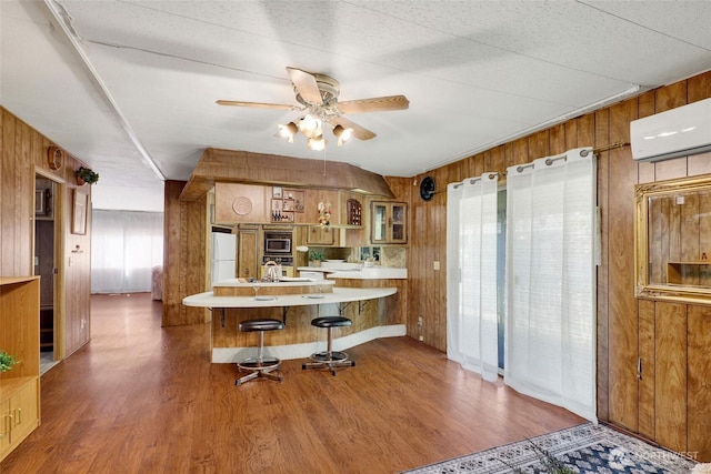 4015 Eliza Ave Unit 47, Bellingham, WA 98226 - kitchen featuring stainless steel microwave, wooden walls, freestanding refrigerator, brown cabinetry, and wood finished floors
