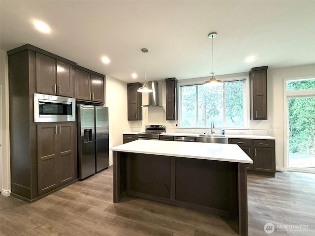 45332 Limestone St, Concrete, WA 98237 - kitchen featuring stainless steel appliances, wall chimney exhaust hood, light countertops, a kitchen island, and wood finished floors