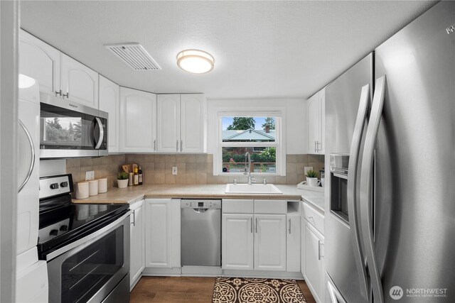 18328 15th Pl NE, Shoreline, WA 98155 - kitchen with stainless steel appliances, light countertops, white cabinets, decorative backsplash, and dark wood finished floors