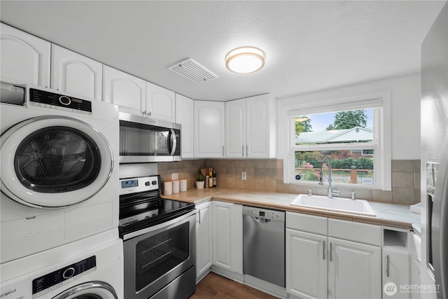 18328 15th Pl NE, Shoreline, WA 98155 - kitchen with stainless steel appliances, stacked washing machine and dryer, tile countertops, white cabinets, and backsplash