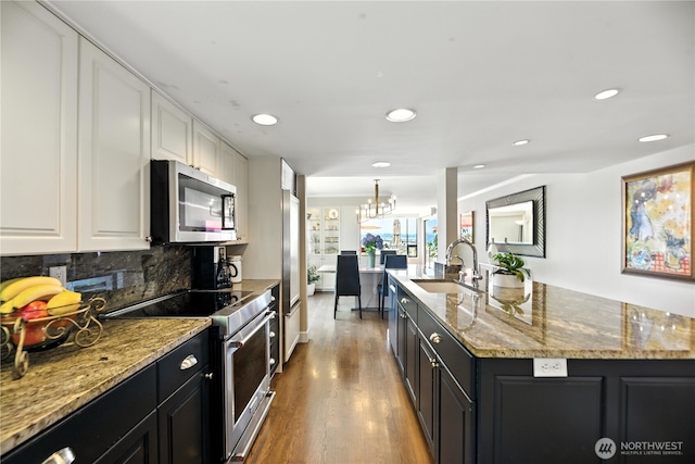 9717 NE Juanita Dr Unit 101, Kirkland, WA 98034 - kitchen featuring appliances with stainless steel finishes, dark cabinets, white cabinetry, an island with sink, and recessed lighting