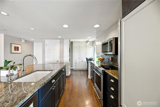 9717 NE Juanita Dr Unit 101, Kirkland, WA 98034 - kitchen with appliances with stainless steel finishes, dark wood finished floors, recessed lighting, stone countertops, and dark cabinets