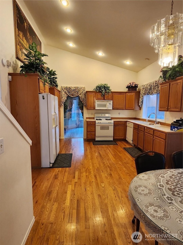 22528 100th Ave SE, Kent, WA 98031 - kitchen featuring white appliances, light countertops, light wood-type flooring, vaulted ceiling, and brown cabinets