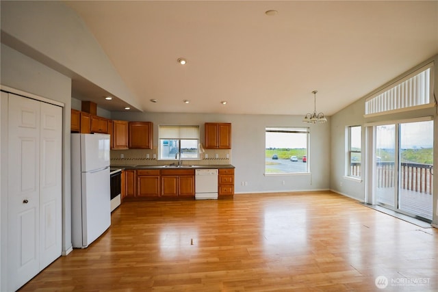 1488 Ocean Shores Blvd SW, Ocean Shores, WA 98569 - kitchen with white appliances, a chandelier, light wood-style floors, brown cabinetry, and healthy amount of natural light