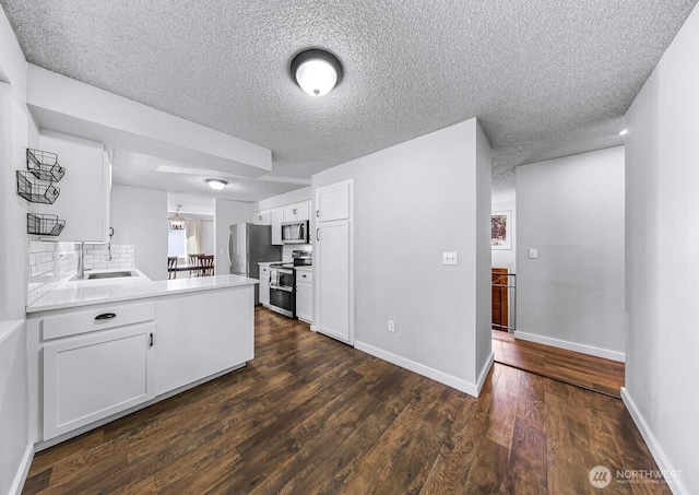 4402 Clearwater Dr SE, Lacey, WA 98503 - kitchen with appliances with stainless steel finishes, a peninsula, white cabinets, a textured ceiling, and dark wood-style flooring