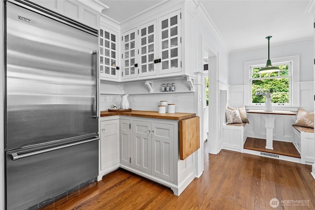 7016 Fremont Ave N, Seattle, WA 98103 - kitchen featuring built in refrigerator, butcher block counters, crown molding, dark wood finished floors, and glass insert cabinets