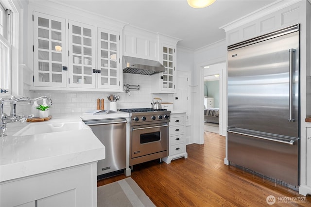 7016 Fremont Ave N, Seattle, WA 98103 - kitchen featuring high quality appliances, extractor fan, white cabinetry, tasteful backsplash, and dark wood-style floors