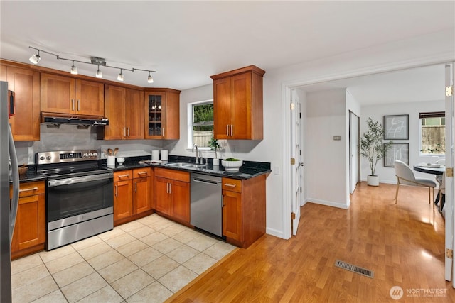 204 Duvall Ave SE, Renton, WA 98059 - kitchen featuring stainless steel appliances, brown cabinetry, under cabinet range hood, light wood finished floors, and glass insert cabinets