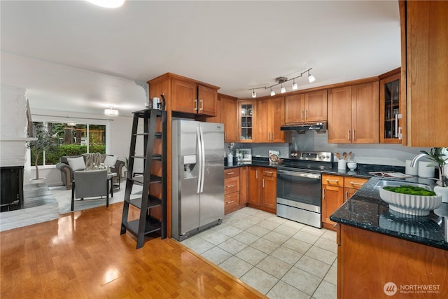 204 Duvall Ave SE, Renton, WA 98059 - kitchen featuring stainless steel appliances, brown cabinets, under cabinet range hood, dark stone countertops, and glass insert cabinets
