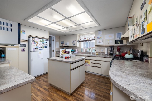 1710 E Highland Ave, Mount Vernon, WA 98273 - kitchen with freestanding refrigerator, gas stove, dark wood finished floors, a kitchen island, and white cabinetry